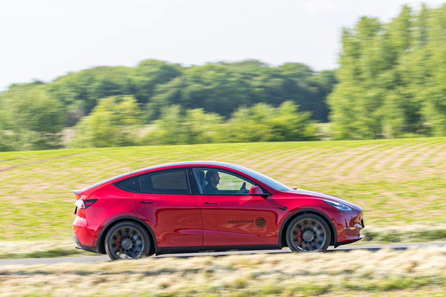 Red Tesla Model Y driving right side